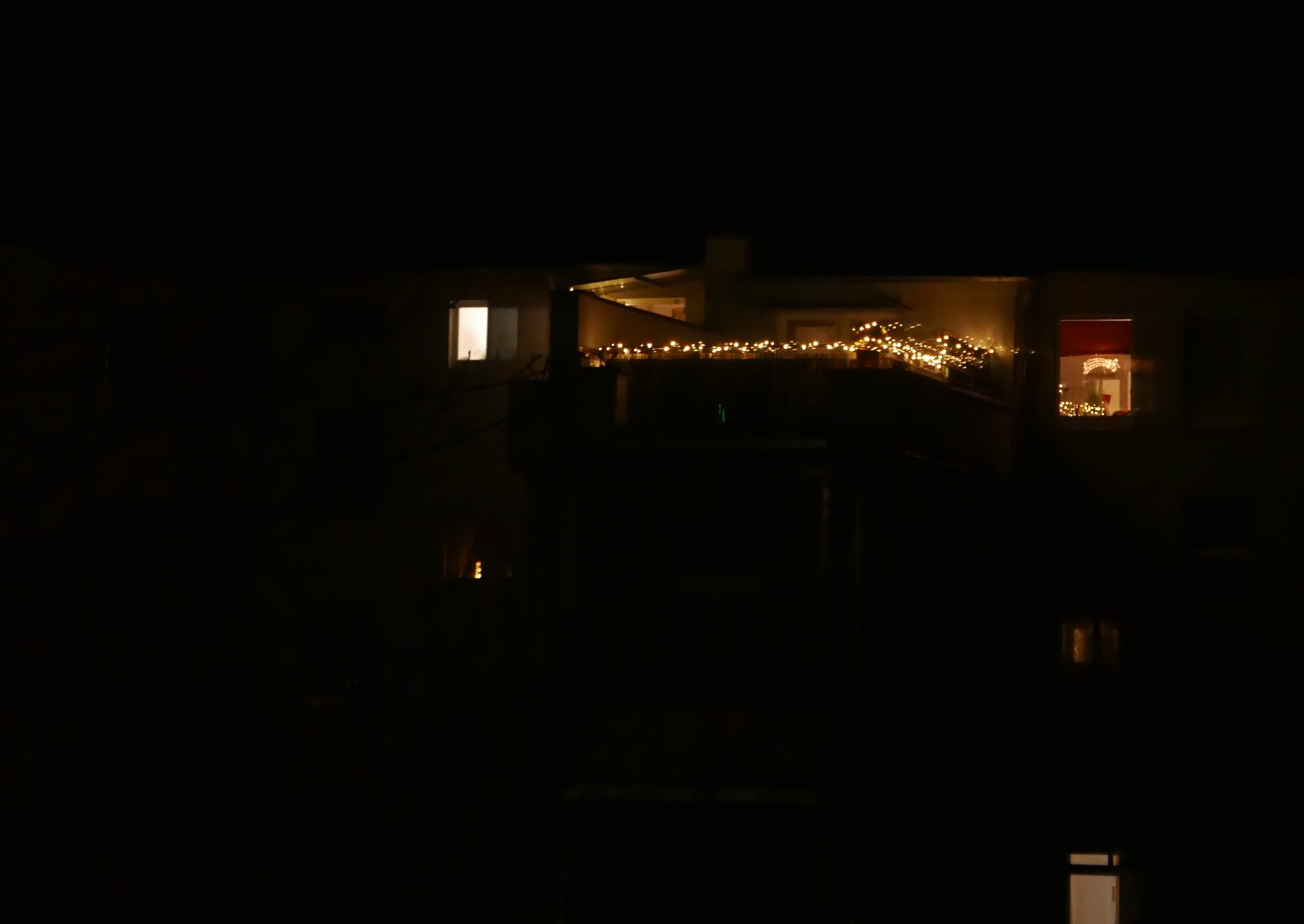 Lichterketten weihnachtlich in der Dunkelheit zwischen Fenstern