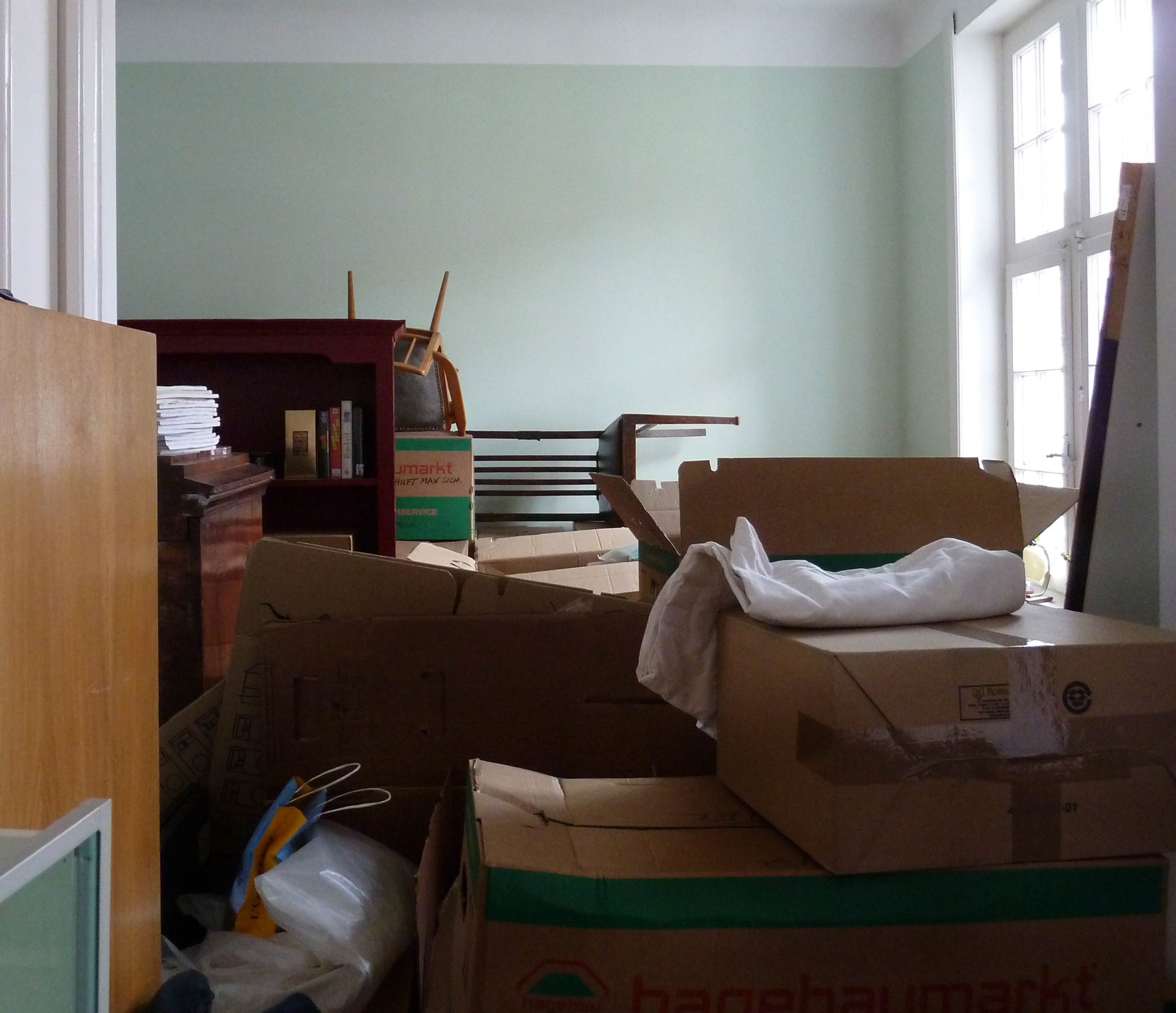 Ansicht eines Zimmers mitten im Umzug mit gestapelten Möbeln und Kartons