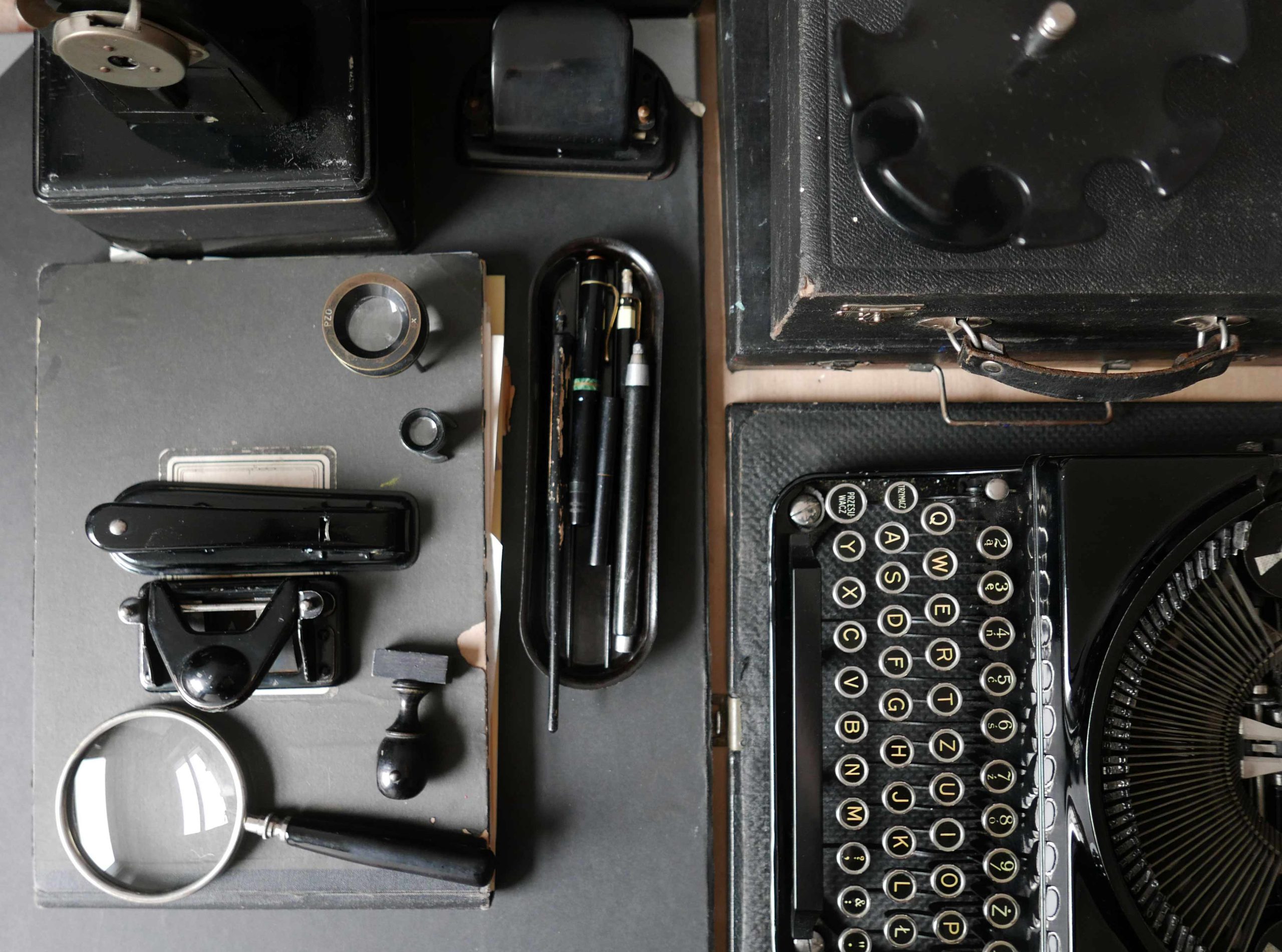 Ansicht einer Schreibtischoberfläche mit schwarzen Büroutensilien und Schreibmaschine