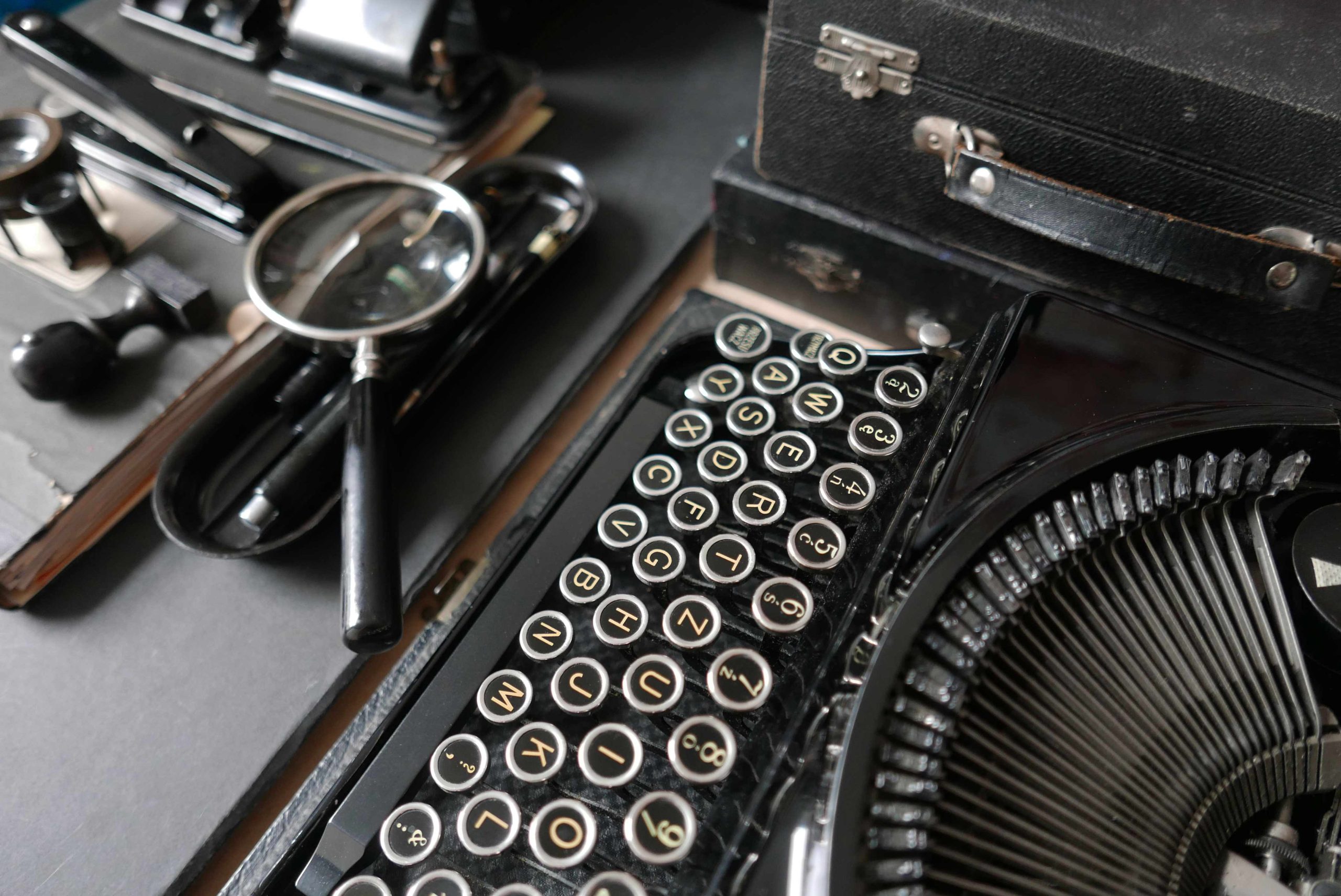 Schrägansicht auf die Tastatur der antiken Remington Schreibmaschine und andere Utensilien des schwarzen Büros